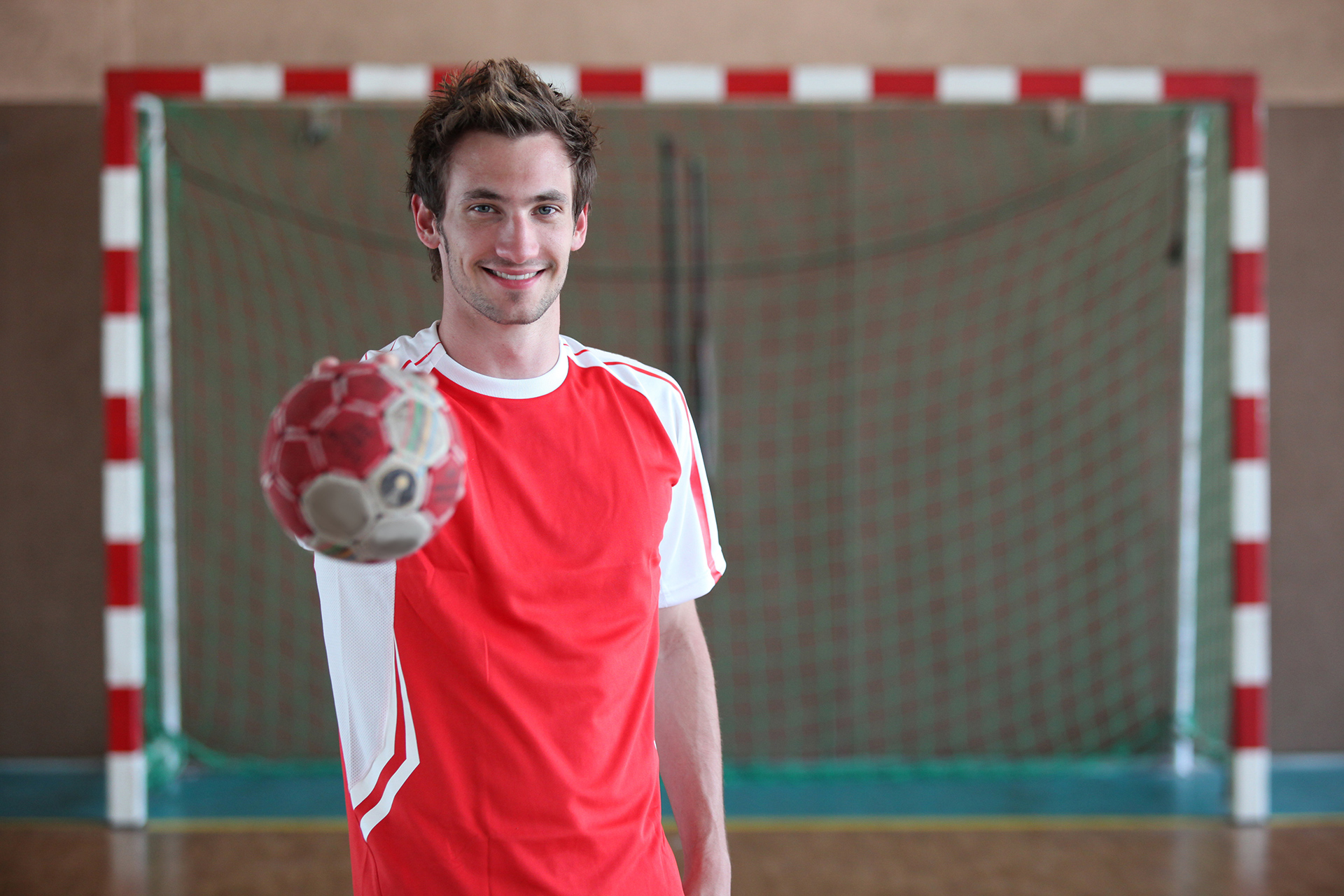 Handballspieler mit Ball und Tor im Hintergrund